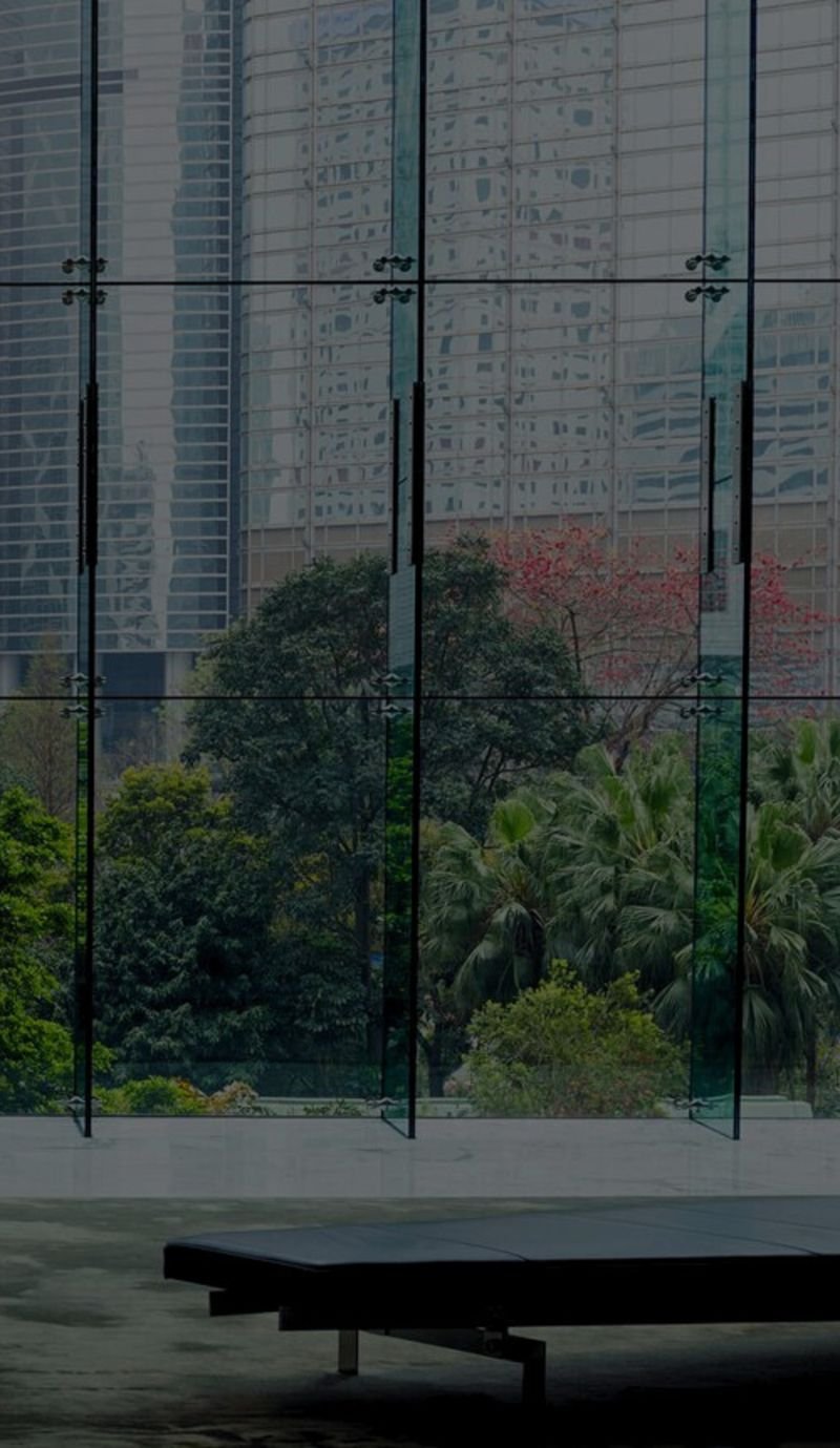 Glass atrium overlooking city towers and a tropical garden